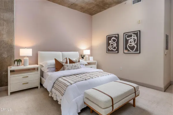 a bedroom with a bed and a lamp on dresser