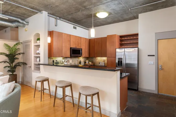 a kitchen with stainless steel appliances granite countertop a refrigerator a stove and a wooden cabinets