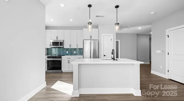 a kitchen with stainless steel appliances kitchen island granite countertop a refrigerator and a stove top oven