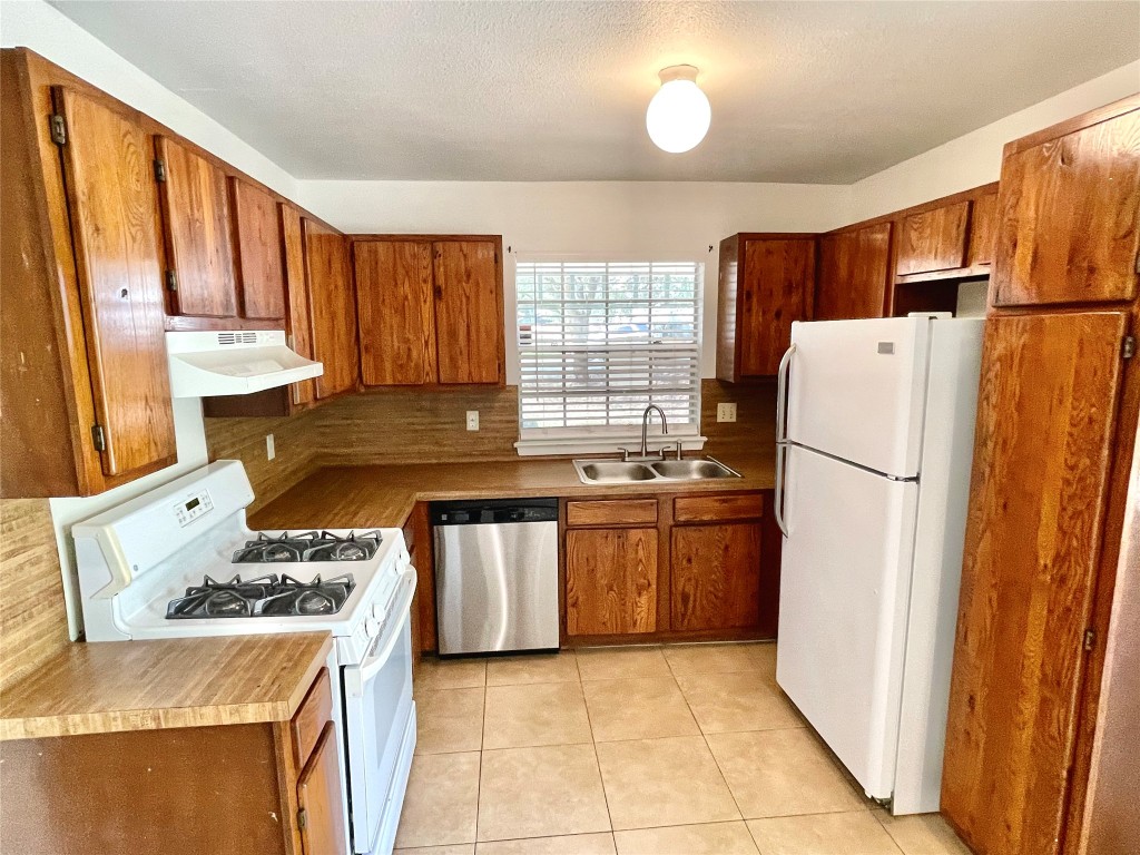 1802 Prairie Knoll Court, Unit B Austin, TX 78758 - Photo 4 of 10 a kitchen with a stove a refrigerator and a sink