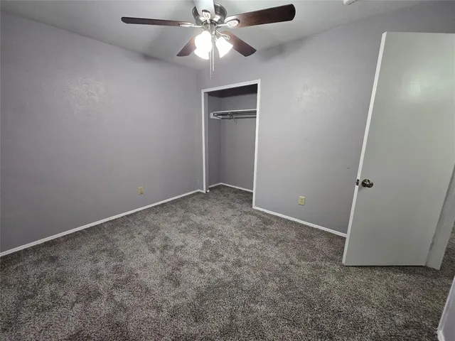an empty room with closet and a chandelier fan