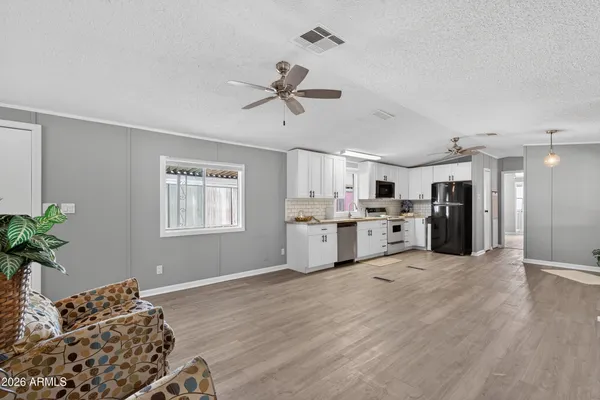 a large white kitchen with stainless steel appliances kitchen island granite countertop a refrigerator a stove a sink dishwasher and white cabinets with wooden floor