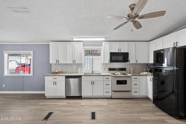a kitchen with stainless steel appliances granite countertop a stove top oven a sink dishwasher and a refrigerator with wooden floor