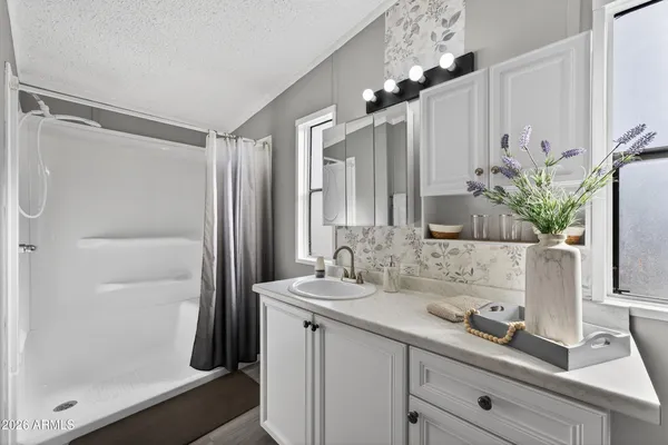 a bathroom with a granite countertop sink a mirror and a shower