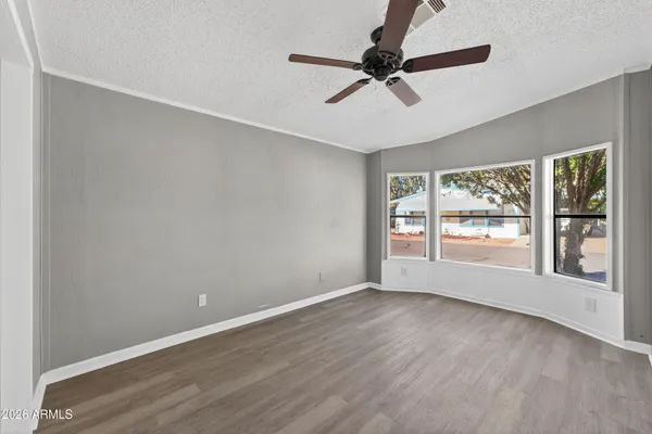 an empty room with wooden floor fan and windows