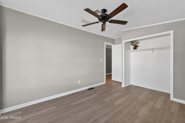 an empty room with wooden floor and ceiling fan