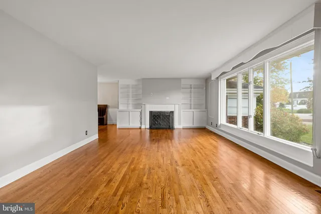 a view of empty room with wooden floor and fireplace