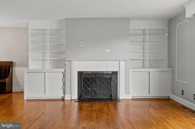 a view of an empty room with wooden floor and a fireplace