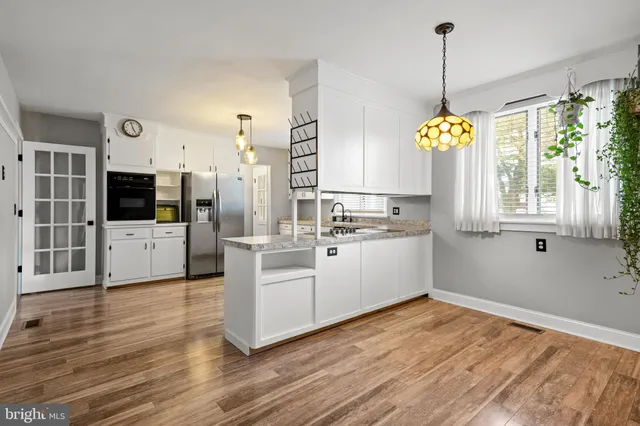 a kitchen that has a lot of white cabinets and wooden floor