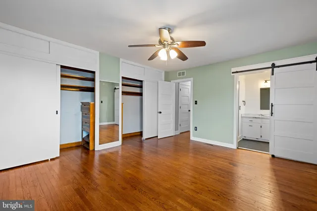 an empty room with wooden floor closet and windows