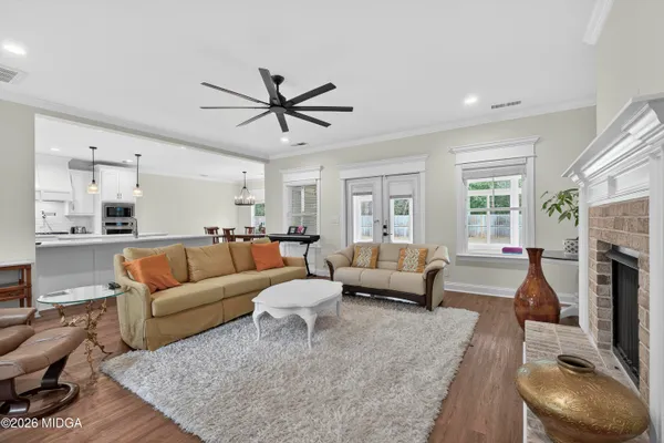 a large white kitchen with a stove a sink dishwasher and a fireplace with wooden floor