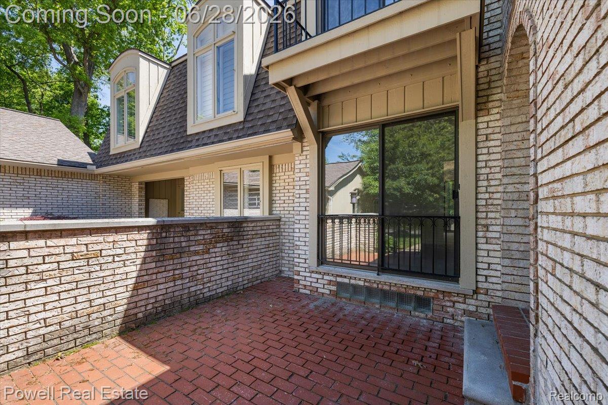 1447 Ravineview Court, Unit C12 Bloomfield Hills, MI 48304 - Photo 5 of 49 Exterior patio featuring red brick pavers, brick walls, and a sliding glass door with an ornamental iron railing