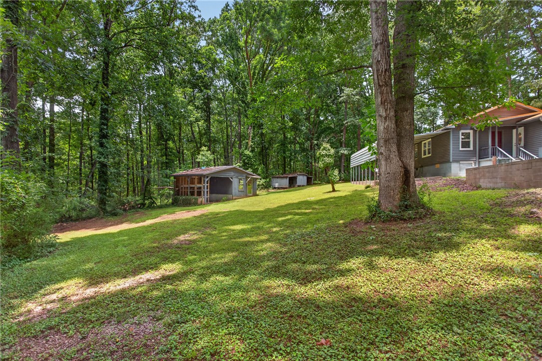 230 Dickard Road Seneca, SC 29672 - Photo 25 of 25 A spacious, verdant yard extends towards the tree-lined property, with several outbuildings offering versatile usage.