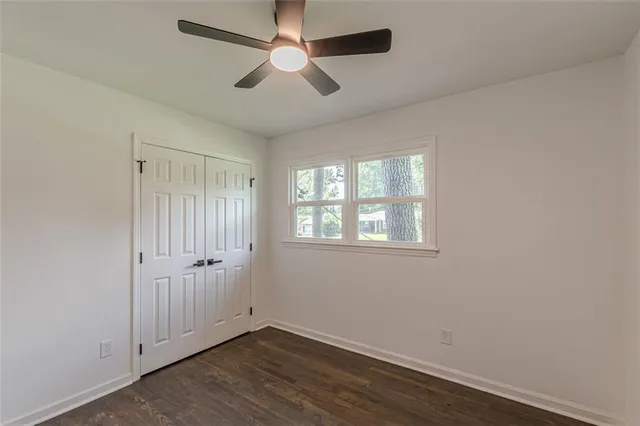 an empty room with wooden floor ceiling fan and windows
