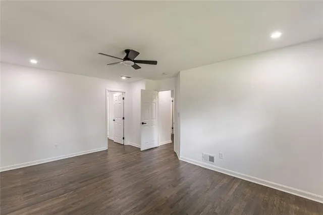 an empty room with wooden floor and ceiling fan