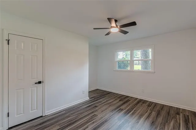 an empty room with wooden floor a ceiling fan and windows