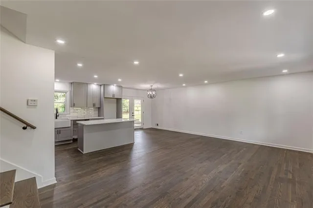 an empty room with wooden floor and kitchen view
