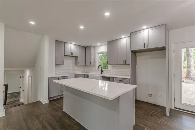 a large white kitchen with a sink a refrigerator and wooden floor