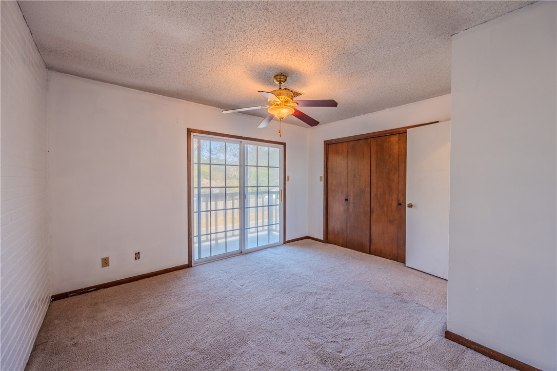 2002 South Lubbock Street Brenham, TX 77833 - Photo 24 of 26 Unfurnished bedroom featuring carpet floors, a textured ceiling, a closet, access to exterior, and a ceiling fan