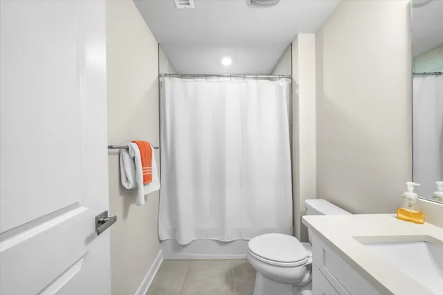 a white toilet sitting next to a bathroom sink and vanity