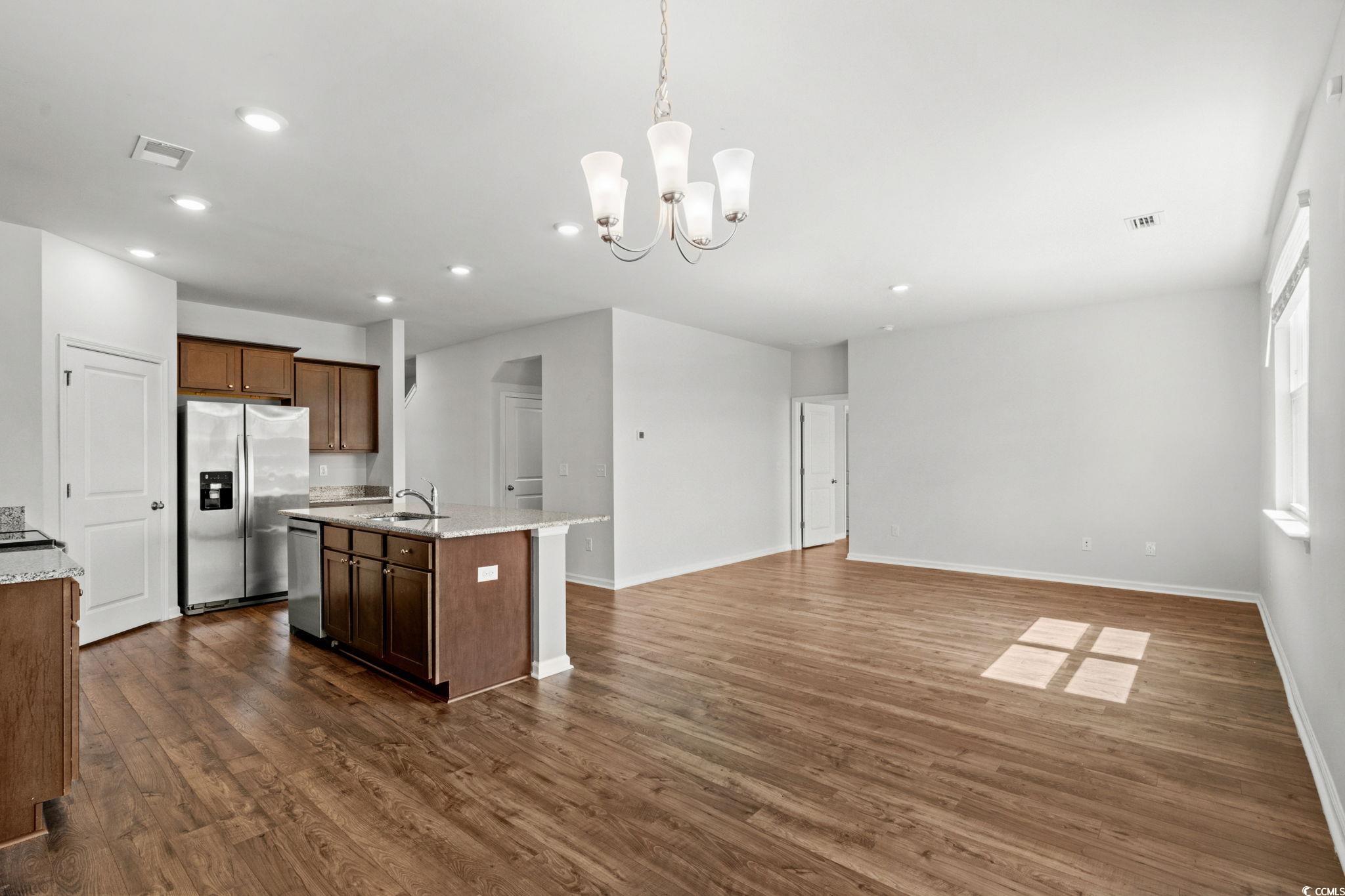2631 Ophelia Way Myrtle Beach, SC 29577 - Photo 12 of 40 Kitchen with hanging light fixtures, a chandelier, appliances with stainless steel finishes, dark wood-style flooring, and light stone countertops