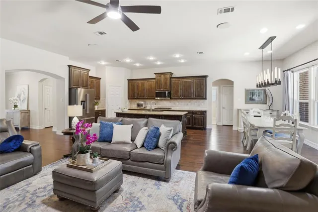 a kitchen with stainless steel appliances granite countertop a stove top oven a sink dishwasher a refrigerator and cabinets with wooden floor