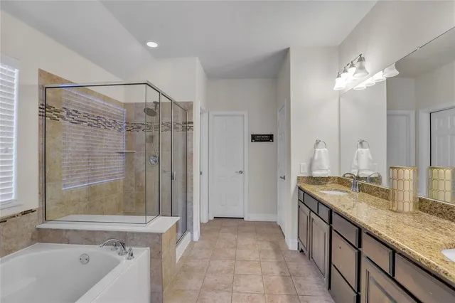 a bathroom with a granite countertop sink a mirror a bathtub and shower