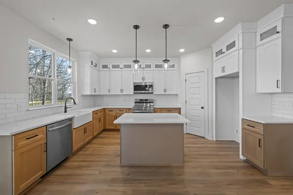 a large kitchen with stainless steel appliances granite countertop a stove a sink dishwasher and a refrigerator with wooden floor