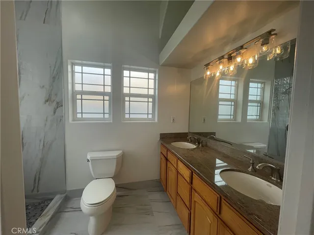 a bathroom with a granite countertop sink toilet and mirror