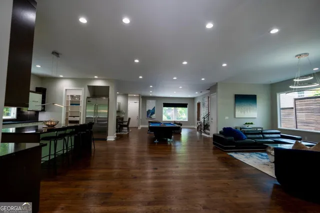 a living room with furniture kitchen view and a wooden floor