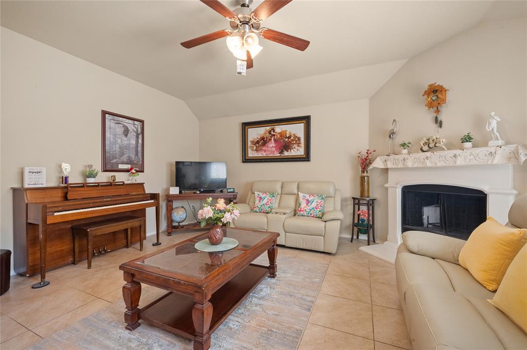 520 Rustic Oak Lane McKinney, TX 75072 - Photo 19 of 30 Spacious living area featuring a vaulted ceiling with a ceiling fan, a fireplace with a decorative mantel, and tile flooring