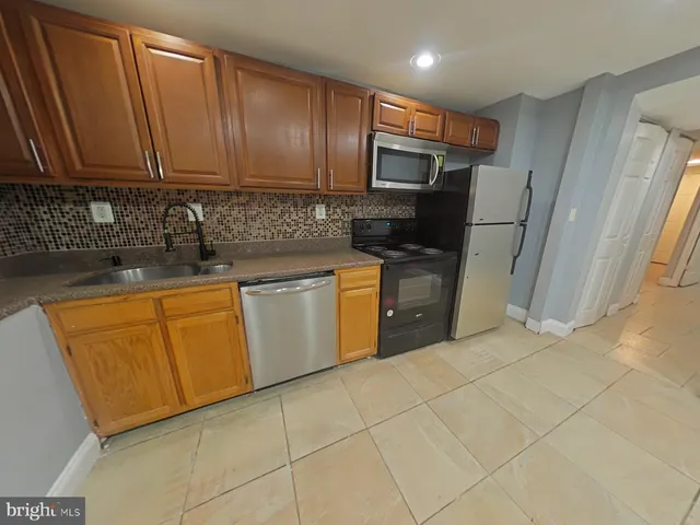 a kitchen with stainless steel appliances granite countertop a sink a stove a refrigerator a microwave oven with white cabinets