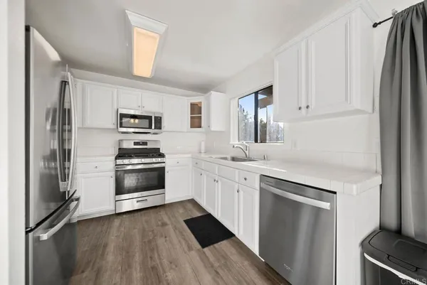 a kitchen with white cabinets and stainless steel appliances