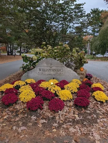 a front view of a building with garden and trees