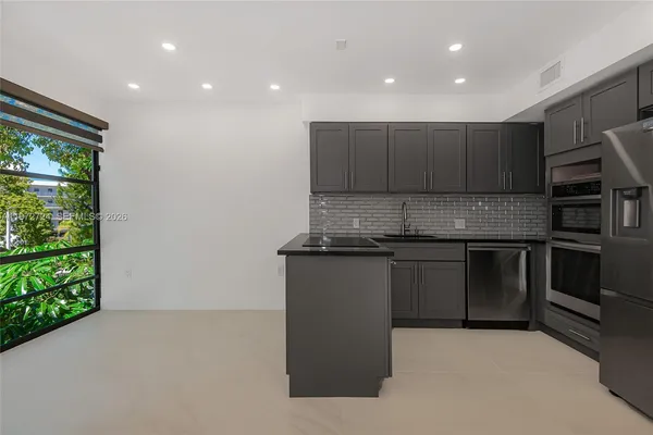 a kitchen with stainless steel appliances granite countertop a stove a sink and a refrigerator with wooden floor