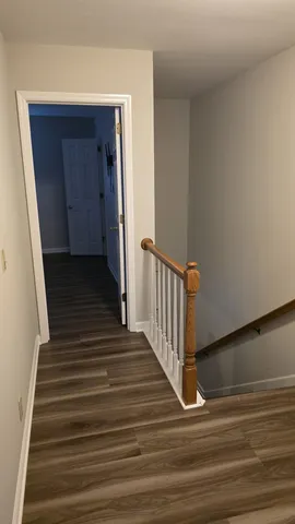 a view of a hallway with wooden floor and staircase