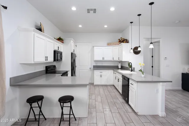 a kitchen with stainless steel appliances kitchen island a white cabinets and wooden floor