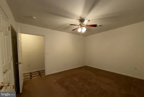 a view of an empty room with chandelier fan and a window