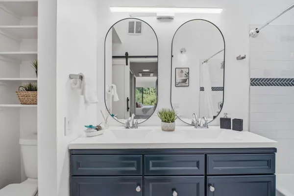 a bathroom with a double vanity sink mirror and shower