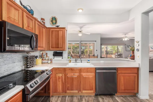 a kitchen with stainless steel appliances granite countertop a stove top oven a sink dishwasher and a microwave oven with large wooden cabinets