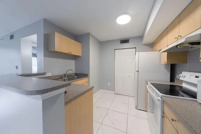 a kitchen with stainless steel appliances granite countertop a sink and a refrigerator