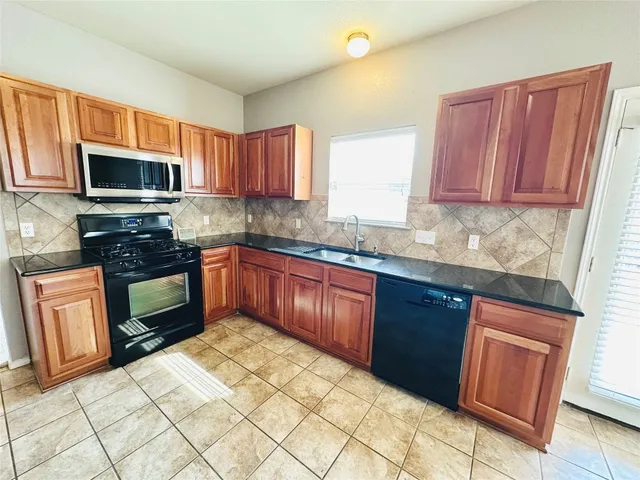 a kitchen with stainless steel appliances granite countertop a stove sink microwave and window