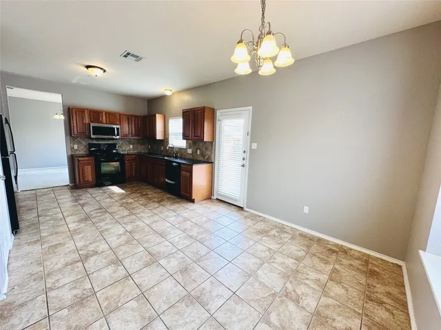 a large kitchen with kitchen island granite countertop a refrigerator a stove a sink dishwasher a dining table and chairs with wooden floor