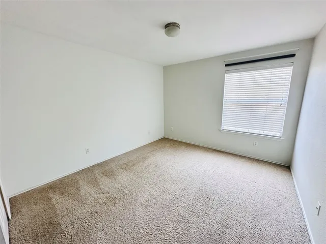 an empty room with a chandelier fan and windows