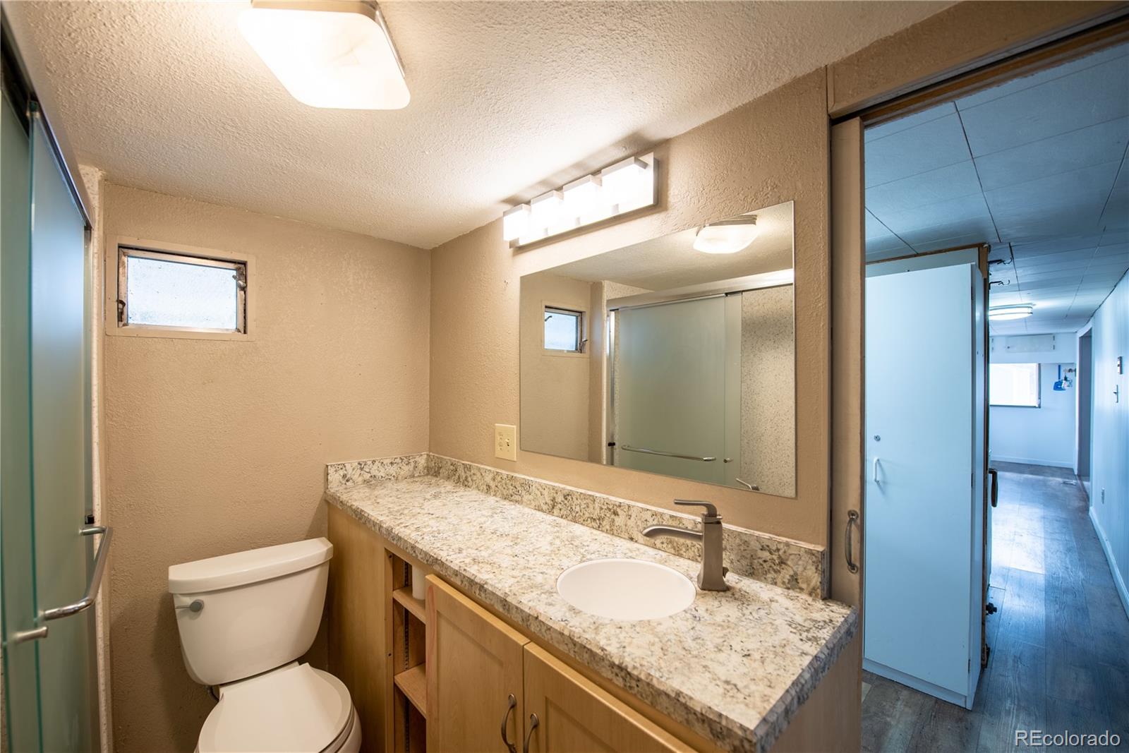 122 Neal Road Bailey, CO 80421 - Photo 15 of 25 a bathroom with a granite countertop toilet a sink and a mirror