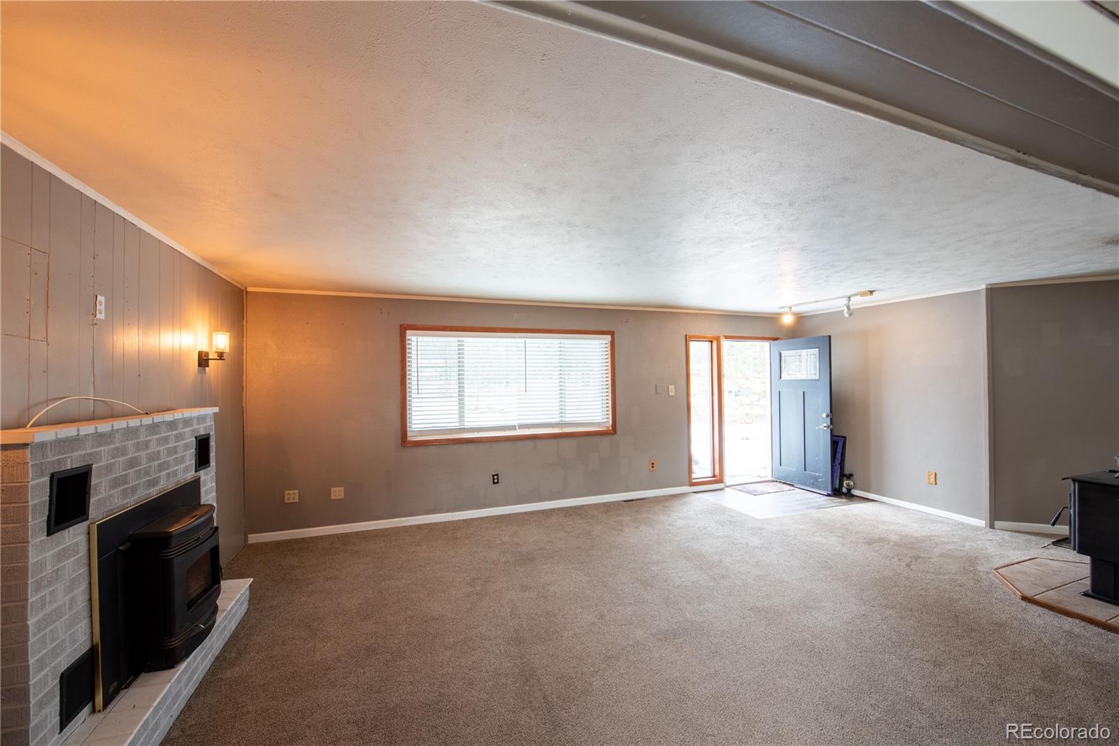 122 Neal Road Bailey, CO 80421 - Photo 5 of 25 a view of an empty room with a fireplace and a window