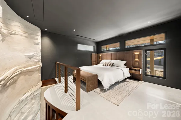 a bed sitting in a spacious bedroom next to a window