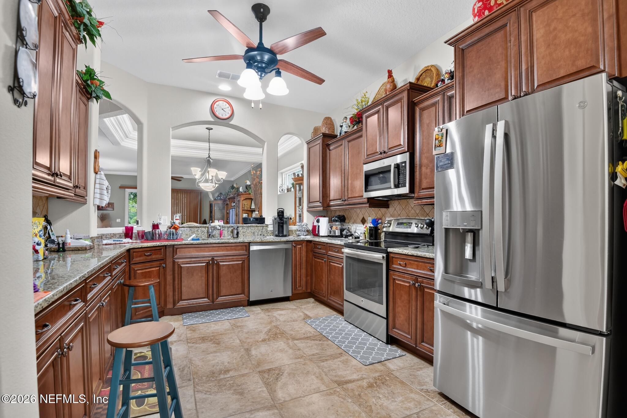 110 Vía Roma Ormond Beach, FL 32174 - Photo 14 of 43 a kitchen with stainless steel appliances granite countertop a refrigerator a stove a sink a dining table and chairs with wooden floor