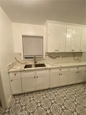 a room with granite countertop cabinets sink and a window