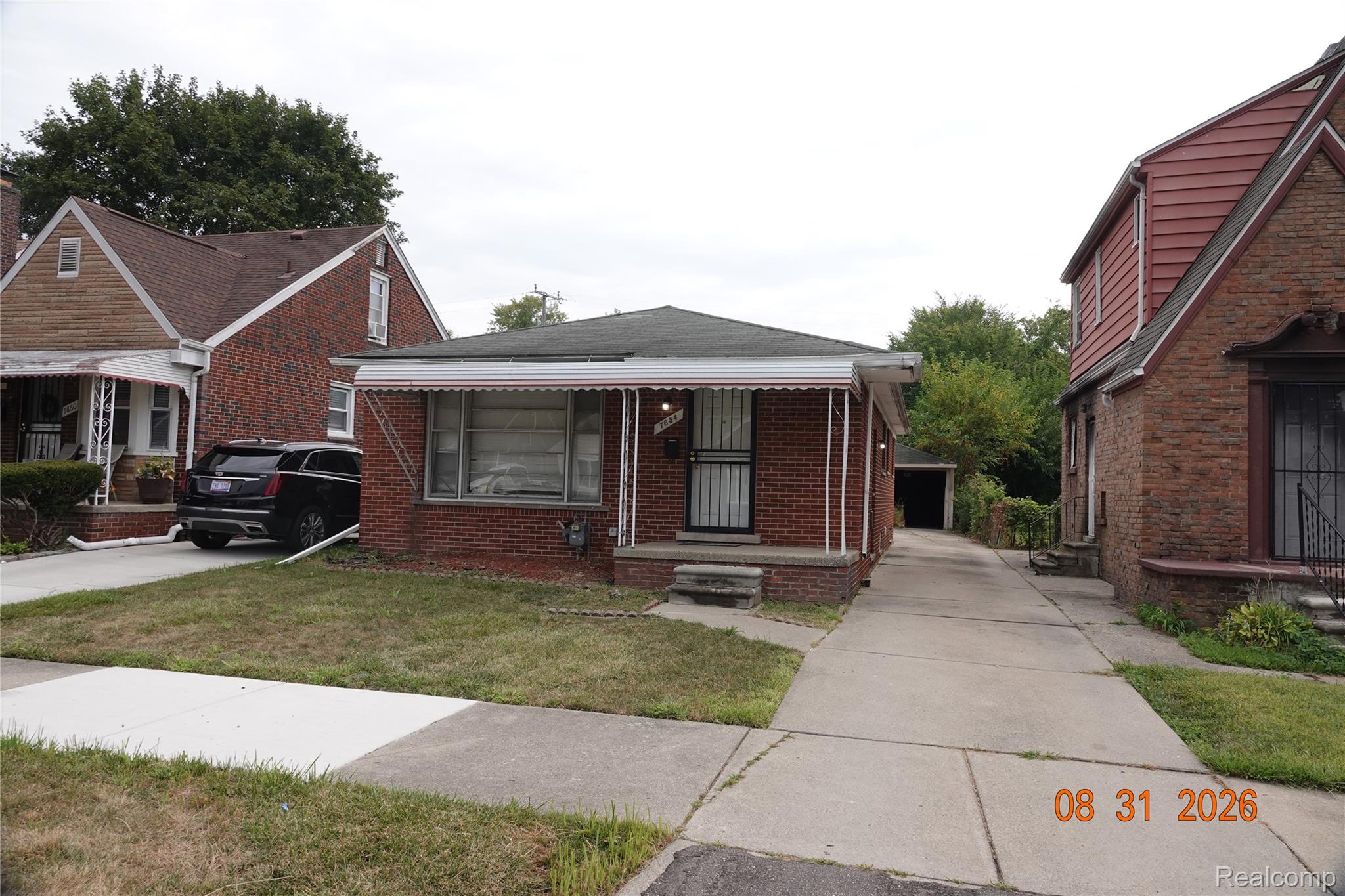 7654 Fielding Street Detroit, MI 48228 - Photo 1 of 23 Brick exterior with a covered front porch, a long concrete driveway, and a detached garage